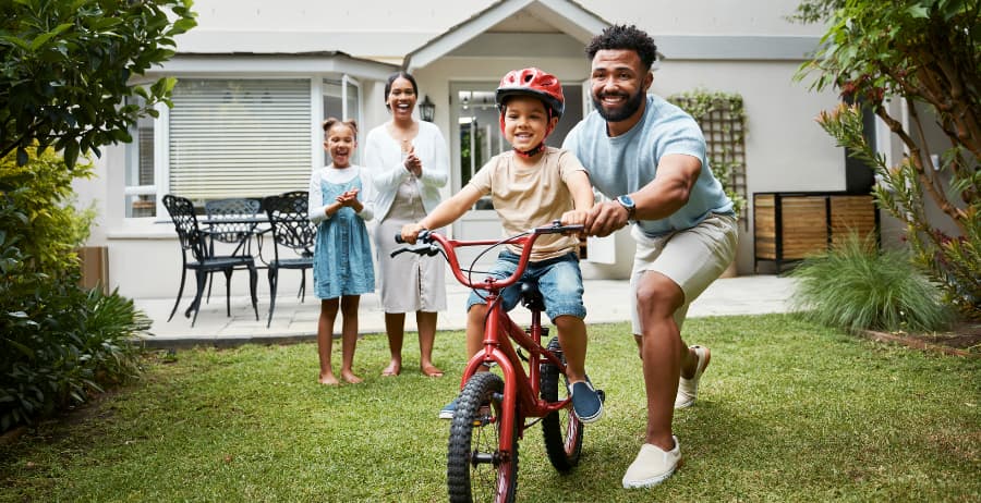Boy learning to ride a bicycle at home with family